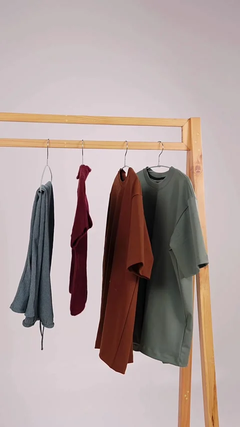 Different colored clothes appear hanging on wooden garment rack Video stock 331773725