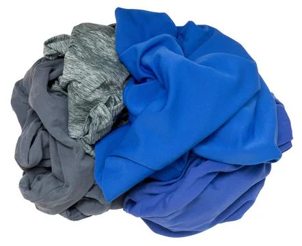 Different colored clothes are wadded together in a messy pile on a plain back 스톡 사진