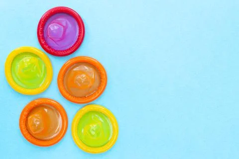 Different colored condoms. Safe or risky sex. Blue background. Protection Stock Photos