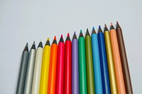 Different colored crayons arranged in a row next to each other. Stock Photos