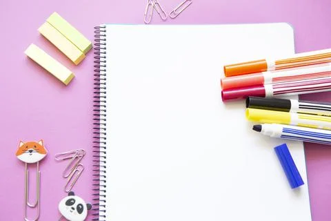 Different colored felt-tip pens and other stationery on blank page of noteboo Stock Photos