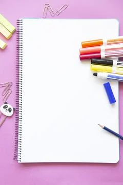 Different colored felt-tip pens and other stationery on blank page of noteboo Stock Photos