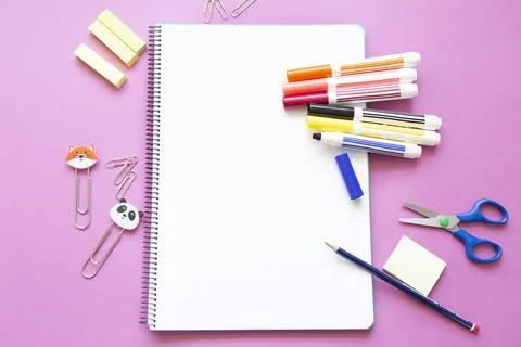 Different colored felt-tip pens and other stationery on blank page of noteboo Stock Photos