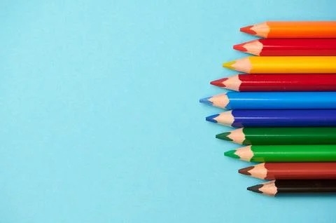Different colored pencils on a light blue background with space for any text Stock Photos