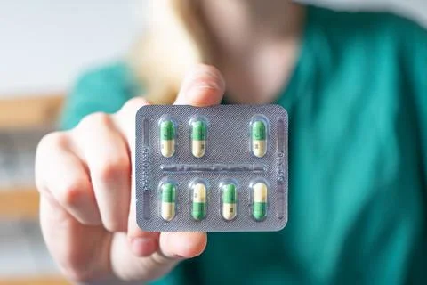 Different colored pills in a hand. Shaking Pills out of a pill bottle. Stock Photos