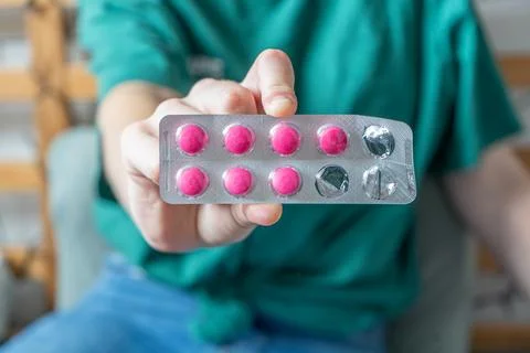 Different colored pills in a hand. Shaking Pills out of a pill bottle. Stock Photos
