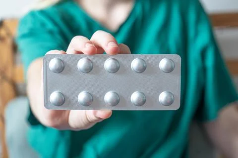 Different colored pills in a hand. Shaking Pills out of a pill bottle. Stockfoto's