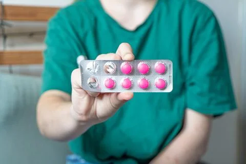 Different colored pills in a hand. Shaking Pills out of a pill bottle. Stock Photos