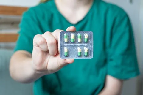 Different colored pills in a hand. Shaking Pills out of a pill bottle. Stock Photos