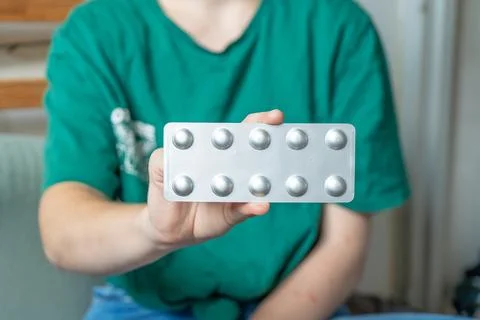 Different colored pills in a hand. Shaking Pills out of a pill bottle. Stock Photos