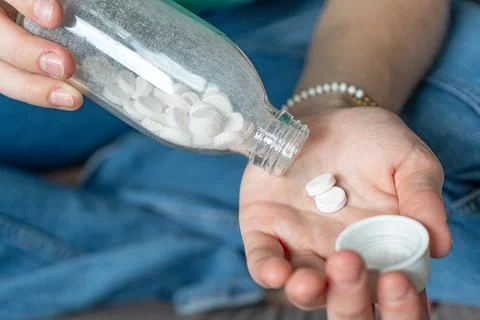 Different colored pills in a hand. Shaking Pills out of a pill bottle. Stock Photos