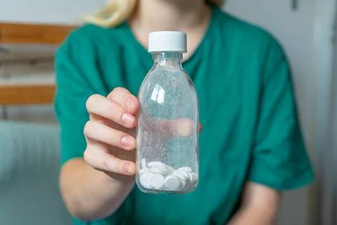 Different colored pills in a hand. Shaking Pills out of a pill bottle. Stockfoto's