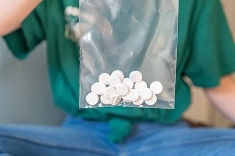 Different colored pills in a hand. Shaking Pills out of a pill bottle. Stock Photos