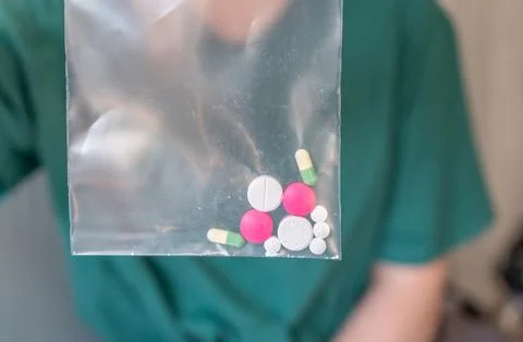 Different colored pills in a hand. Shaking Pills out of a pill bottle. Stock Photos