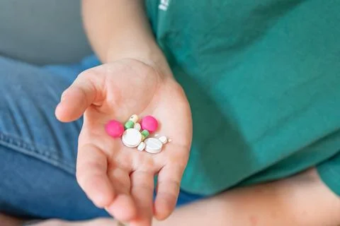 Different colored pills in a hand. Shaking Pills out of a pill bottle. Stock Photos