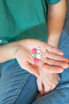 Different colored pills in a hand. Shaking Pills out of a pill bottle. Stock Photos