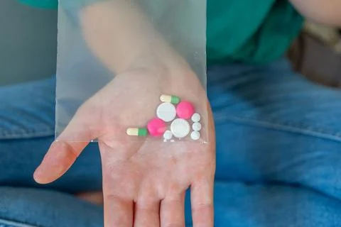 Different colored pills in a hand. Shaking Pills out of a pill bottle. Stock Photos