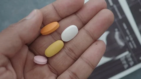 Different colored pills in hand show variety of medications Stock Footage 321327186