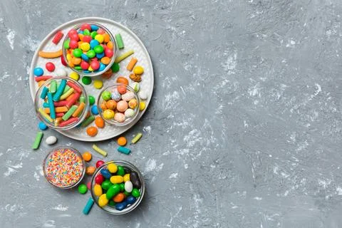 Different colored round candy in bowl and jars. Top view of large variety swe Stock Photos