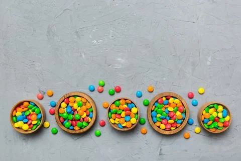 Different colored round candy in bowl and jars. Top view of large variety swe Stock Photos