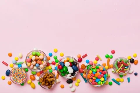 Different colored round candy in bowl and jars. Top view of large variety swe Stock Photos