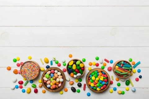 Different colored round candy in bowl and jars. Top view of large variety swe Stock Photos