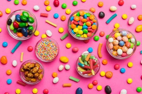 Different colored round candy in bowl and jars. Top view of large variety swe Stock Photos