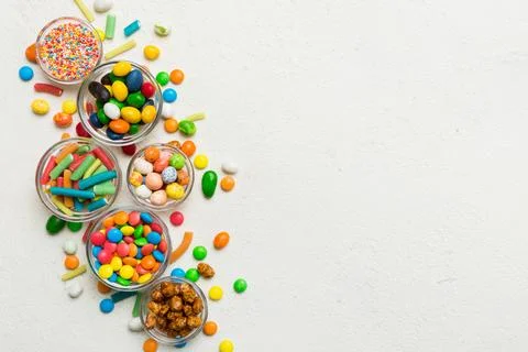 Different colored round candy in bowl and jars. Top view of large variety swe Stock Photos