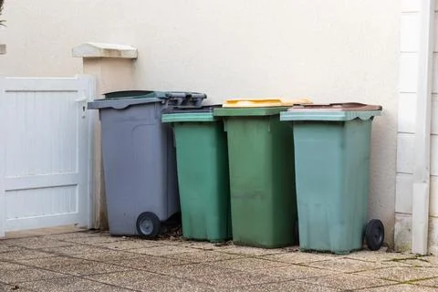 Different colored waste bins are neatly arranged along the side of a resident Stock Photos