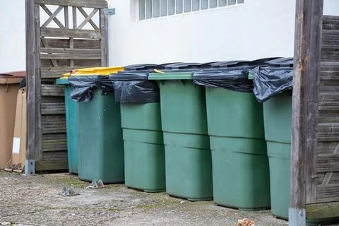 Different colored waste bins are neatly arranged along the side of a resident Stock Photos