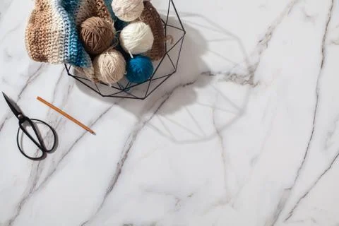 Different colored wool yarn balls and knitted winter scarf with crochet hook in Stock Photos
