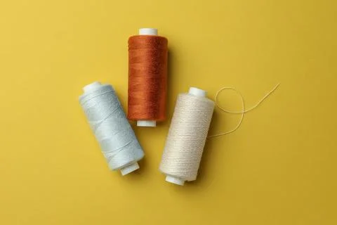 Different colorful sewing threads on yellow background, flat lay Stock Photos