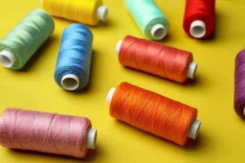 Different colorful sewing threads on yellow background Stock Photos
