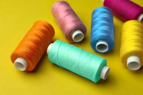 Different colorful sewing threads on yellow background Stock Photos