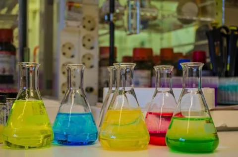 Different colorful solution in conical flask in a chemistry lab with blur bac Stock Photos