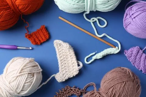 Different colorful yarns, pattern samples and crochet hook on blue backgrou.. Stock Photos