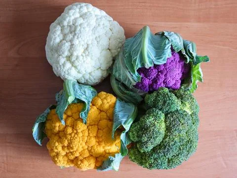 Different colors of cauliflower and broccoli arranged on a wooden surface Stock Photos