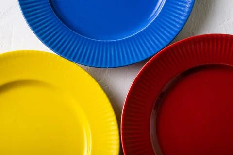 Different colors of empty plates. White background. Red, blue and yellow clay Stock Photos
