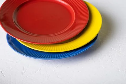 Different colors of empty plates. White background. Red, blue and yellow clay 库存照片