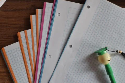 Different colors sheets with a pen in the shape of a student Stock Photos