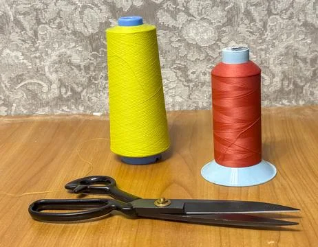 Different colors of thread with scissors on wooden surface Stock Photos