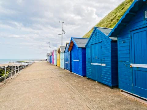 Different coloured beach huts under a grey sky Stock Photos