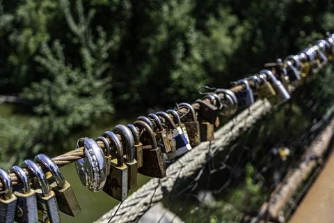 Different coloured locks left on the wire railing of a 100 year old bridge Stock Photos