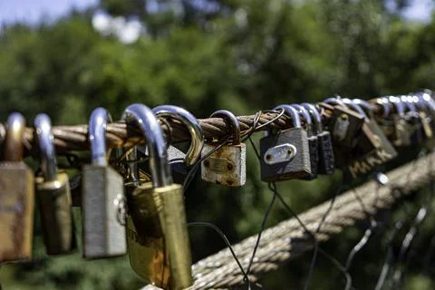 Different coloured locks left on the wire railing of a 100 year old bridge Stock Photos