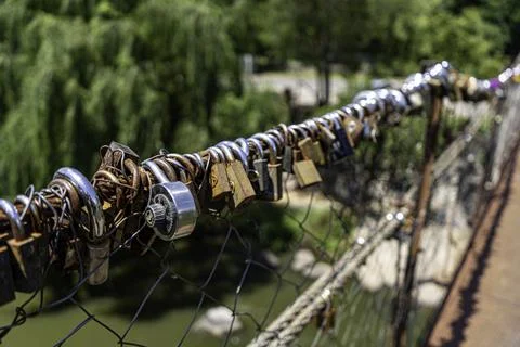 Different coloured locks left on the wire railing of a 100 year old bridge Stock Photos