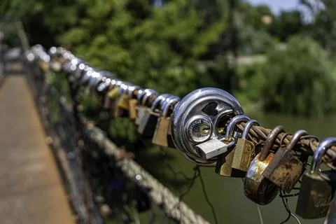 Different coloured locks left on the wire railing of a 100 year old bridge Stock Photos