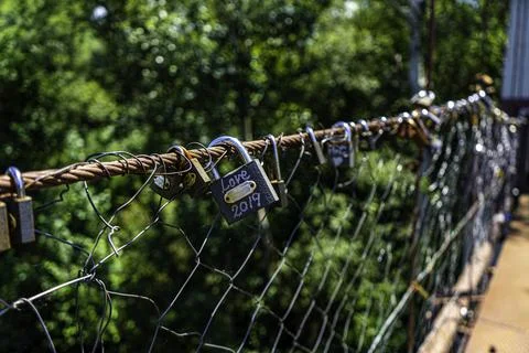 Different coloured locks left on the wire railing of a 100 year old bridge Stock Photos