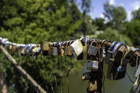 Different coloured locks left on the wire railing of a 100 year old bridge Stock Photos