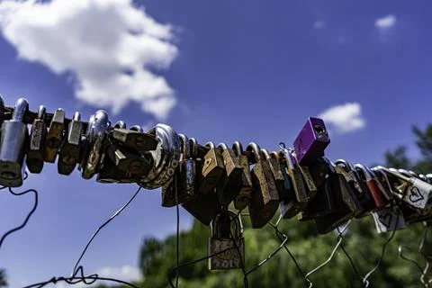 Different coloured locks left on the wire railing of a 100 year old bridge Stock Photos
