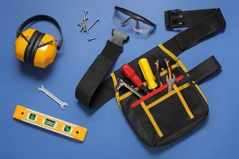 Different construction tools and tool belt on blue background Stock Photos